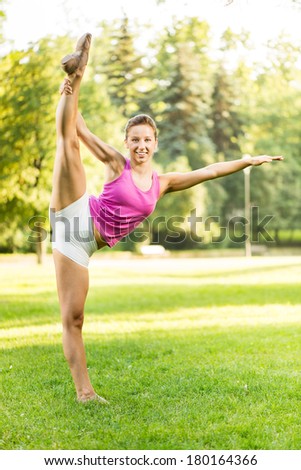 Cute young woman doing Splits exercises in the park.