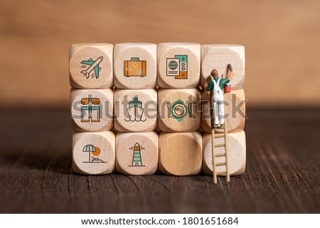 little painter figures and cubes with travel icons on wooden background