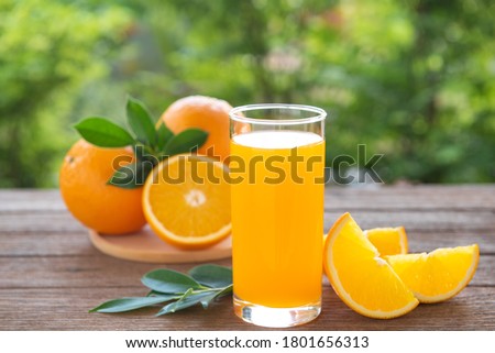 Fresh orange juice in the glass on a wooden table against the natural bokeh background. Royalty-Free Stock Photo #1801656313