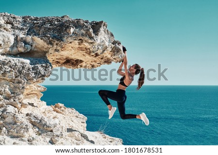 Rock climbing. Sport. Active lifestyle. Athlete woman hangs on sharp cliff. Seascape. Outdoors workout. High resilience Royalty-Free Stock Photo #1801678531