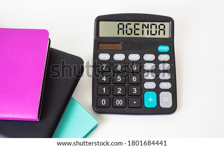 Agenda word, text on calculator, multicolored notepads on white background