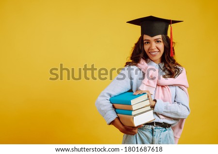 Portrait of young African American woman with books posing on a yellow background. Graduation, university, college, distance education concept.