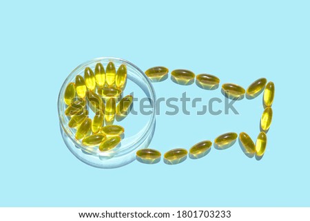Omega3 gel capsule. Yellow vitamin. Health eating. Dietology drug. Fish shape. Oil supplement. Microdosing concept. Golden color softgel collagen. Blue background. Medicine immunity cosmetics