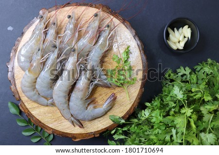 fresh shrimps or white prawns raw on wooden chopping board with coriander and curry leaves. on background with copy space. Royalty-Free Stock Photo #1801710694