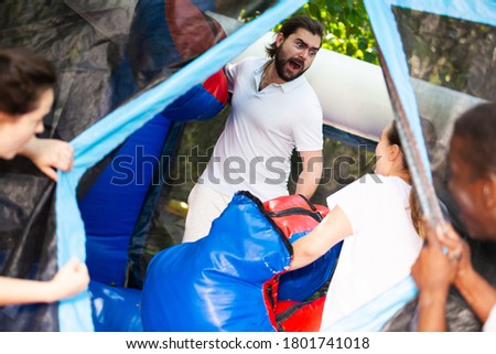 Gambling friends boxing giant gloves on an inflatable trampoline in an amusement park. High quality photo