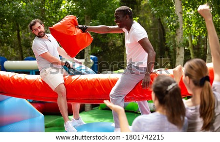 Cheerful pillow fight sitting on a log in an amusement park. High quality photo