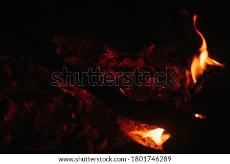 Sparks from the fire and red-hot coals on a black background close-up. Campfire, fire for graphic inserts. Ashes and coals, smoke from the fire.