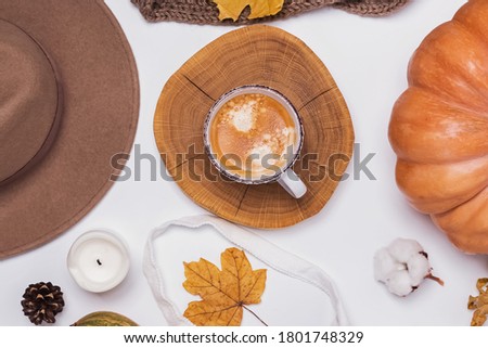 Creative autumn flat lay with cup of coffee, yellow leaves and hat on the white table