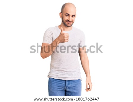 Young handsome man wearing casual t shirt doing happy thumbs up gesture with hand. approving expression looking at the camera showing success. 