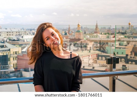 A young woman smiling on the roof with a panorama of Moscow
