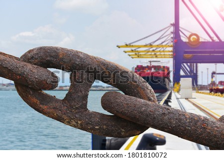 The rusty big anchor chain of the heavy cargo winch A large cargo ship on the background