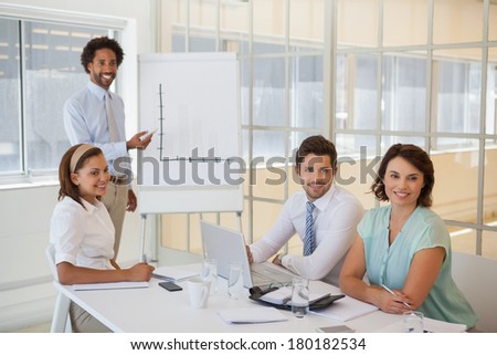 Portrait of a young businessman giving presentation to colleagues in a bright office