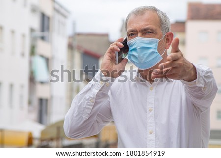 man with medical mask talking with the mobile phone and pointing with the finger