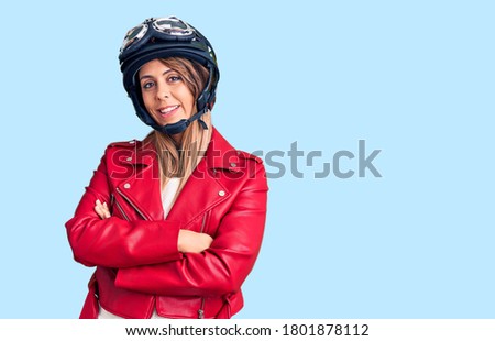 Young beautiful woman wearing motorcycle helmet happy face smiling with crossed arms looking at the camera. positive person. 