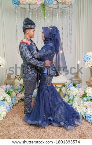 Bride and groom wearing navy blue Malay traditional cloth pose during wedding celebration in Malaysia