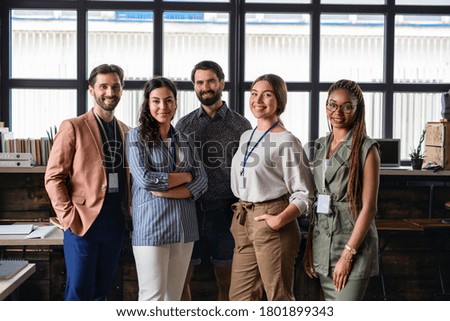 Portrait of young businesspeople standing indoors in office, looking at camera. Royalty-Free Stock Photo #1801899343