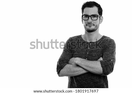 Studio shot of young handsome man wearing eyeglasses with arms crossed