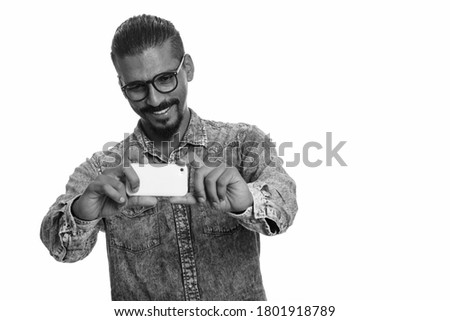 Young happy Indian man taking picture with mobile phone