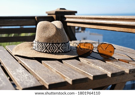 straw hat with sunglasses with on wooden terrace of holiday villa or hotel with sea view