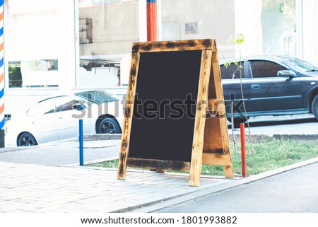 Blank wooden sandwich board at the street near skyscrapers