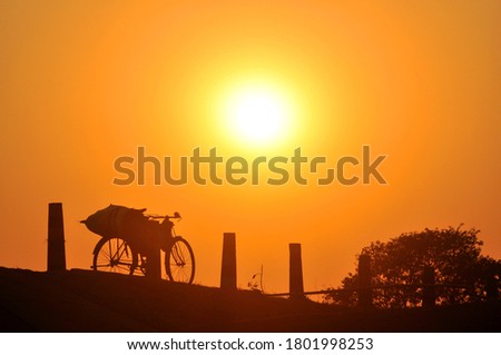 A cycle loaded with personal belongings of a villager in North Bengal, India gets silhouetted during dusk.