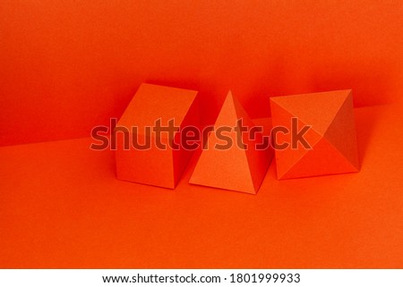 Geometrical figures still life composition. Red pyramid rectangular cube objects on red background. Platonic solids figures, simplicity concept photography.