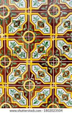 Vertical photo of a vintage tiles with geometric and floral borders in vivid warm color in Aveiro in Portugal