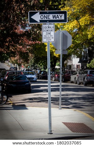 Sidewalk Dismount Zone for bikes and scooters sign on busy shaded autumn street