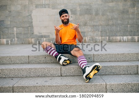 Handsome young stylish hipster guy with beard roller skating outdoors. Recreational activity. Aggressive roller skates