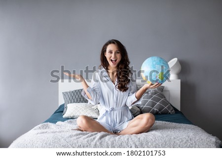 Portrait of a beautiful happy woman with a globe indoors. World is open for travel.