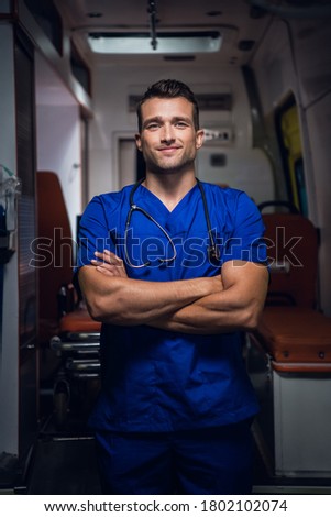A three quarter portrait of a young handsome paramedic with his hands folded.