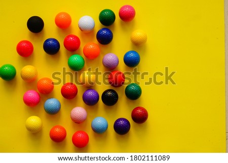 Multicolored golf balls on yellow background. Copy space. Selective focus.                               