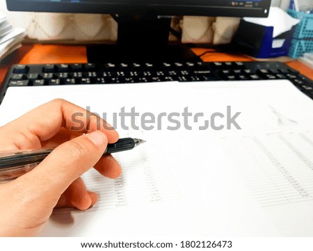 Hand is holding pen while working at office desk. Paperwork at office.Selective focus, blur background.