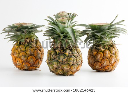 3 small pineapples placed in a row on a white background.