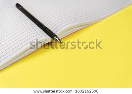 A set of office supplies. Blank notepad and pen isolated on bright yellow background.