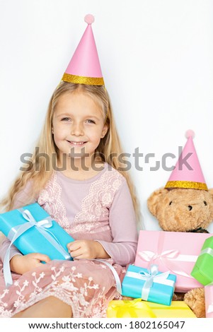Happy kid receiving present on boxing day. Little girl smiling with wrapped present boxes. Small child in pink hat holding birthday gifts isolated on white background. Holiday, celebration concept