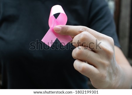 Hand holding Pink Ribbon for supporting people living and illness. Healthcare, October Breast Cancer Awareness month and International Women day concept.