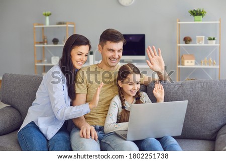 A happy family online communication using a laptop while sitting with the child on the couch at home