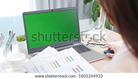 telework concept - back view of asian business woman use laptop with green chroma key screen to join a video meeting or remote work at home