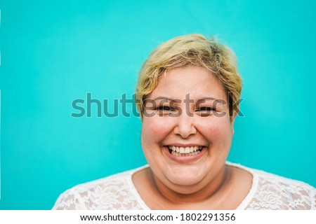 Happy plus-size woman portrait - Curvy overweight lady with turquoise background - Emancipation and confident concept - Focus on face Royalty-Free Stock Photo #1802291356