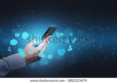 Hand of businesswoman using smartphone over blurry blue background with double exposure of social media interface. Toned image