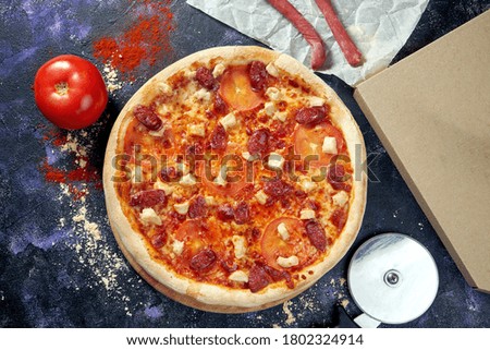 Oven-baked Italian pizza with tomato, bacon and smoked sausages on a dark background