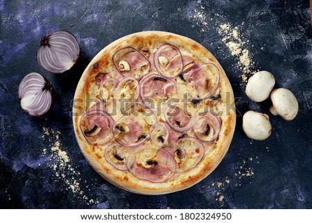 Oven baked italian pizza with melted cheese, ham, mushrooms, onions and carbonara sauce on a dark background
