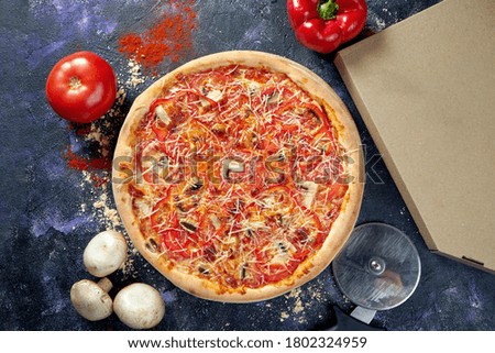 Oven baked italian veggie pizza with melted cheese, onions, mushrooms and tomatoes on a dark background