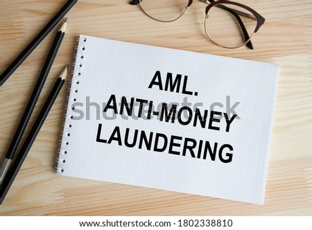 The inscription in the Anti-money laundering- AML notebook, a pen and glasses next to it.