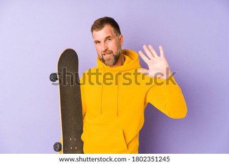Senior skater man isolated on purple background smiling cheerful showing number five with fingers.
