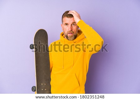 Senior skater man isolated on purple background being shocked, she has remembered important meeting.