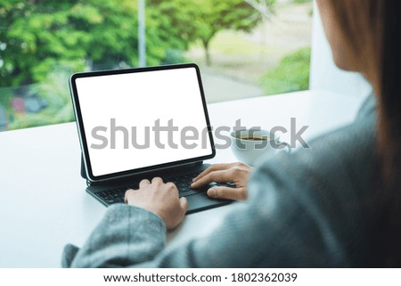 Mockup image of a businesswoman using and typing on digital tablet keyboard with blank white desktop screen as a computer pc in office