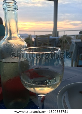 Bottle and a glass of white wine on sunset