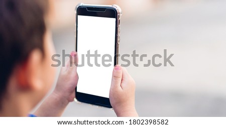 Cute little boy child using technology of smartphone outdoors.Kid felling relaxing and enjoy time play phone with white mockup blank screens.Communication and technology concept